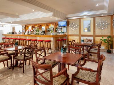 Gezellige hotelbar met houten meubels, bar, heldere verlichting en decoratieve muren.