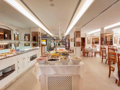 Jasna jadalnia z bufetem i nakrytymi stołami w hotelu.