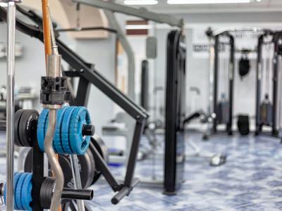 Een moderne fitnessruimte met gewichten en krachttrainingsapparaten op een patroonvloer.