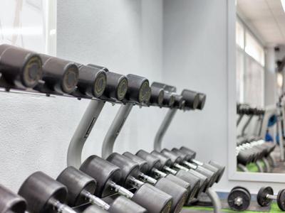 Sportschool met een rij halters voor een grote spiegel