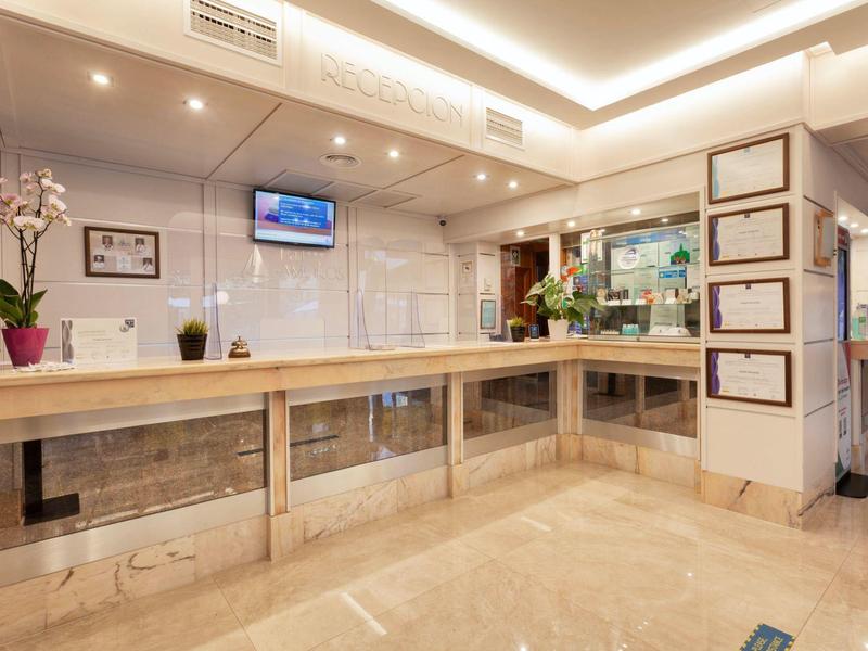 Jasne lobby hotelowe z długim drewnianym kontuarem i nowoczesnym oświetleniem