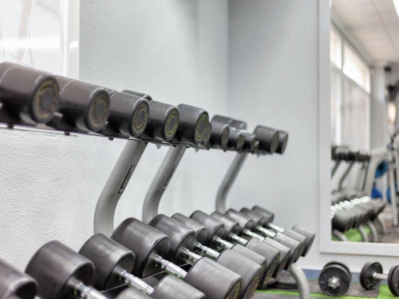 Rząd hantli przed dużym lustrem na siłowni hotelowej.