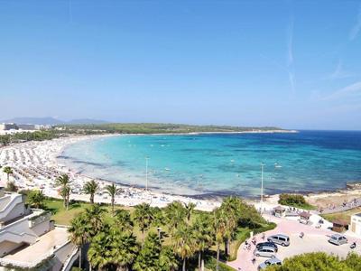 Strand mit klarem blauem Wasser, weißem Sand und Palmen unter blauem Himmel