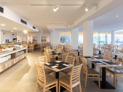 Helles, modernes Hotelrestaurant mit Holzmöbeln und Buffetbereich bei Tageslicht.