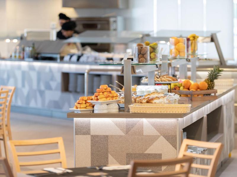 Bufet s pečivem a čerstvým ovocem v moderním hotelovém prostředí.