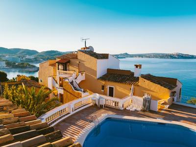 Villa mit Pool und Meerblick bei Sonnenuntergang in einer Küstenregion.