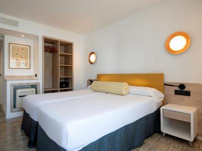 Modern hotel room with a large double bed, nightstand, and built-in wardrobe.
