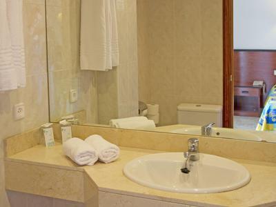 Łazienka hotelowa z umywalką, lustrem i złożonymi ręcznikami na blacie.