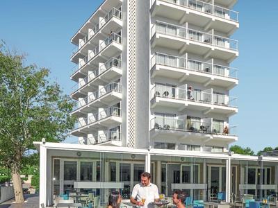 Modern multi-story hotel building with outdoor terrace and guests.