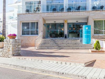 Treppen führen zum Eingang eines häuslichen Gebäudes mit Steingeländer und bepflanzten Kübeln.