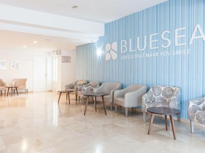 Bright waiting area at Blue Sea Hotel with armchairs and blue accent wall design.