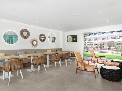 Jasna część wypoczynkowa z krzesłami i lustrami na ścianie w nowoczesnym hotelu.