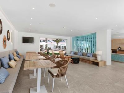 Nowoczesna jadalnia z drewnianymi stołami, krzesłami i wygodną ławką w jasnej, otwartej przestrzeni.