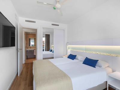 Nowoczesny pokój hotelowy z dużym łóżkiem, białymi ścianami i drewnianą podłogą.