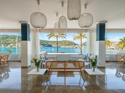 Jasna, otwarta restauracja z widokiem na morze i palmy, nowoczesne meble ze szkła i drewna.