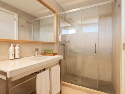 Modernes Badezimmer mit großer Dusche, Waschbecken, Spiegel und Handtüchern.