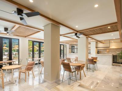 Licht restaurant met houten meubels en grote ramen met uitzicht op bergen.