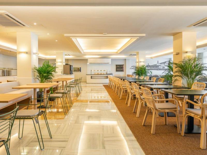 Ristorante luminoso e moderno con tavoli e sedie in legno, piante e molta luce naturale