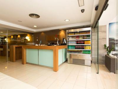 Moderner Hotel-Empfangsbereich mit glattem Boden, Holztheke und Kühlschrank mit Getränken.