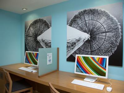 Moderner Arbeitsbereich mit zwei Computern und Wandkunst auf türkisfarbener Wand