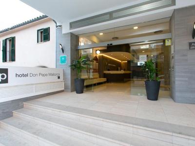 Eingangsbereich eines Hotels mit großen Glasfenstern, Treppenstufen und dekorativen Pflanzen.