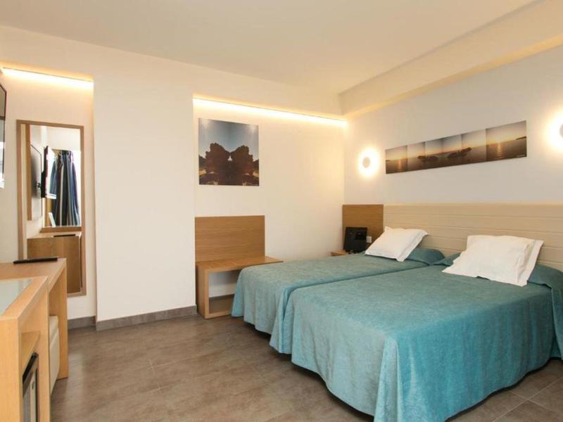 Hotelový pokoj s dvěma jednolůžky, moderním nábytkem a měkkým osvětlením.