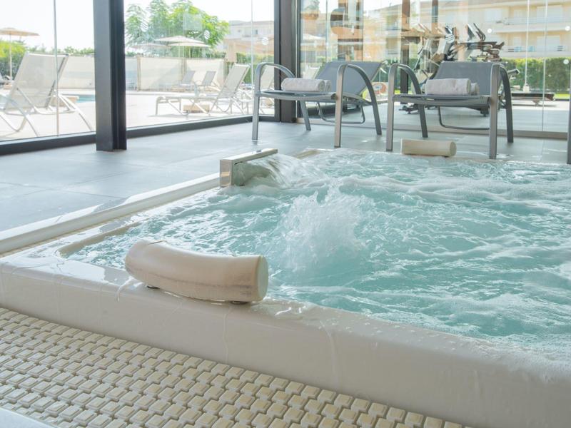 Moderner Indoor-Whirlpool mit sprudelndem Wasser, Kopfstützen und großen Fenstern im Hintergrund.