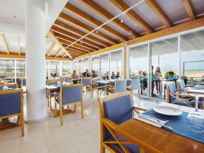 Helles, modernes Restaurant mit Holzstühlen, blauen Polstern und großen Panoramafenstern.