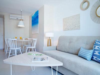 Bright living room with gray sofa, white table, dining table, and modern decorations.
