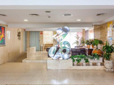 Intérieur d'hôtel lumineux avec sculpture moderne et plantes.