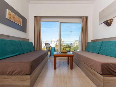 Wohnzimmer mit zwei langen Sofas, Kleinem Holztisch und großer Glas-Schiebetür zum Balkon.