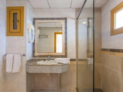 Kompaktes Badezimmer mit Waschbecken, großem Spiegel, Handtuchhalter, Glas-Dusche und Fenster.