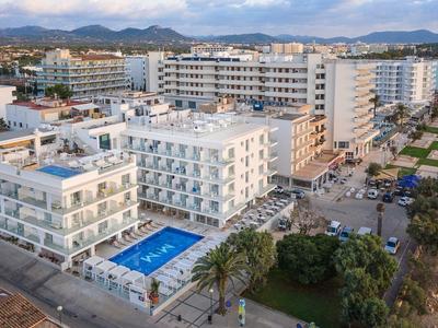 Mehrstöckige Hotels mit Außenpool, Palmen und Bergen im Hintergrund bei klarem Himmel.