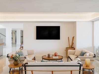 Lichte woonkamer met banken, aan de muur gemonteerde tv en decoratieve tafel in een hotelkamer.