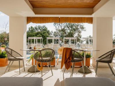 Terras met stoelen en tafels met uitzicht op een tuin met paviljoens in een hotel.