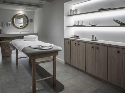 Moderne wellnessruimte met massagetafel en verlichte planken.