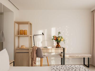 Lichte, moderne hotelkamer met bureau, stoel en decoratieve bloemen.