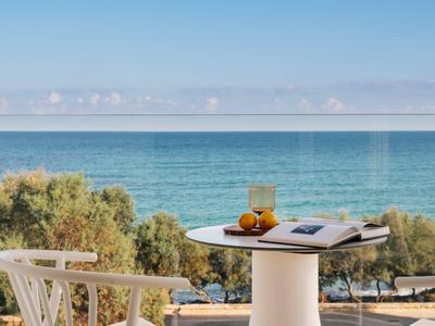 Balkon met tafel, twee sapglazen en sinaasappels met uitzicht op zee bij heldere lucht.
