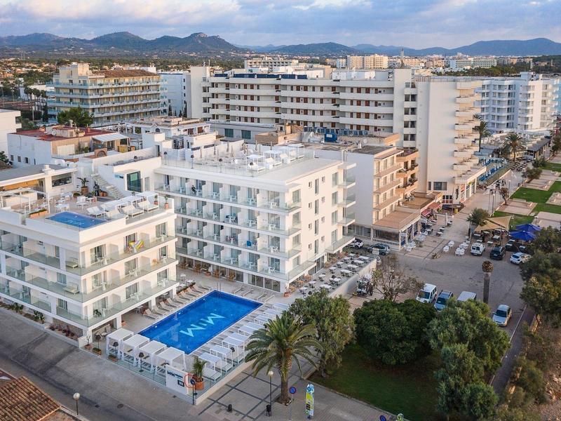 Wielopiętrowe hotele z basenami i górami w tle w kurorcie.