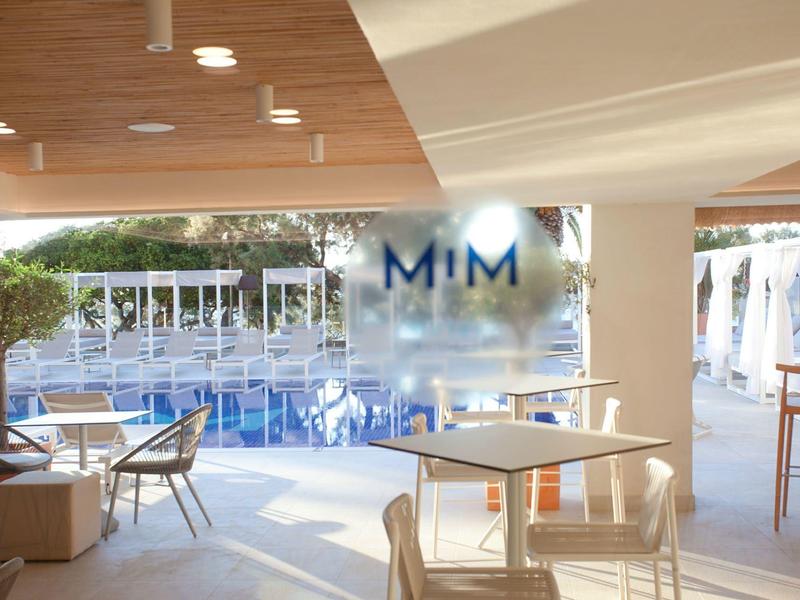 Nowoczesna przestrzeń hotelowa z miejscami do siedzenia i widokiem na basen na zewnątrz.