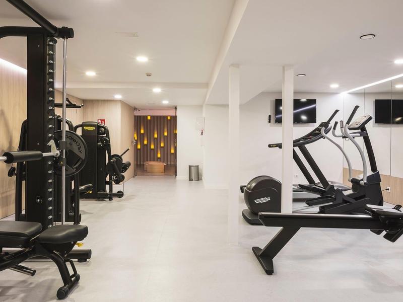 Nowoczesna siłownia z różnymi maszynami do ćwiczeń i jasnym oświetleniem.