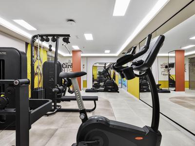 Moderner Fitnessraum mit verschiedenen Trainingsgeräten und großen Spiegeln.