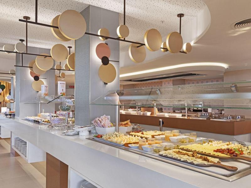 Moderner Buffetbereich mit vielfältigen Speisen, hellem Design und runden Lampen an der Decke.