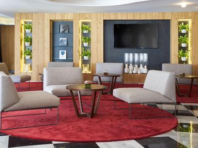 Moderní společenský prostor s pohodlnými křesly, červeným kobercem a velkou televizí.