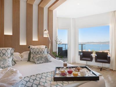 Moderní hotelový pokoj s manželskou postelí, výhledem na moře a snídaňovým podnosem na posteli