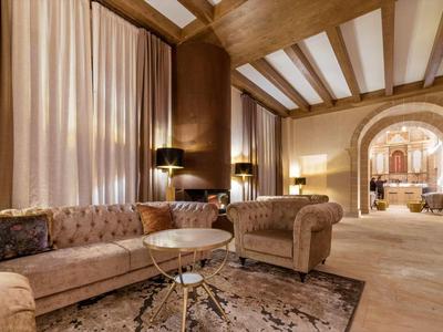 Accogliente lounge con divani in velluto marrone, soffitto con travi in legno e pavimento moquettato in un hotel.
