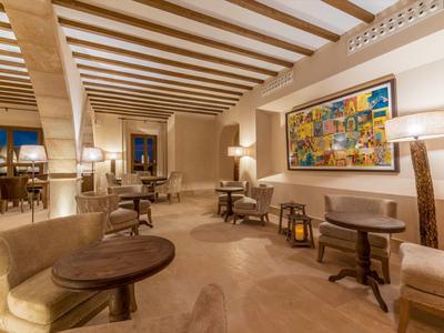 Area lounge accogliente con poltrone comode, tavoli in legno e illuminazione calda.