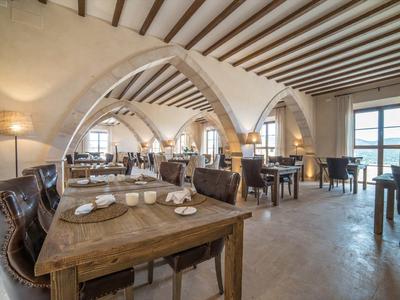 Ristorante luminoso con tavoli in legno, archi in mattoni e vari spazi per sedersi.