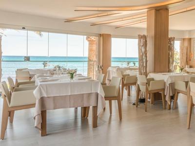 Helles Restaurant mit Blick aufs Meer, gedeckte Tische und bequeme Stühle.