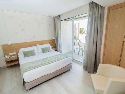 Jasny pokój hotelowy z łóżkiem podwójnym, balkonem i nowoczesnym wyposażeniem.